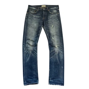 Uniqlo jeans med slitningar - Säljer ett par blå jeans från Uniqlo med snygga slitningar och lätt tvättad look. Klassisk femficksmodell med raka ben och normal passform. Jeansen är tillverkade i 100% bomull och har knapp- och dragkedjegylf.