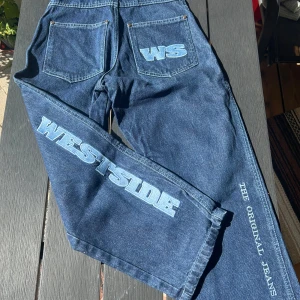 West Side blå jeans med tryck - Säljer dessa unika vintage jeans med West Side prints 💙 säljer pga att det inte är min stil längre, väldigt fint skick!  Innerbenslängd: 67 cm Midjemått: 70 cm Finns i DM för bilder/ frågor, köpare står för frakt 🚚 