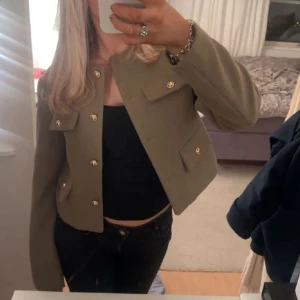 Olivgrön blazer från Zara M - Supersnygg och höstig blazer från Zara i  olivgrön med guldknappar som funkar som en lätt jacka också