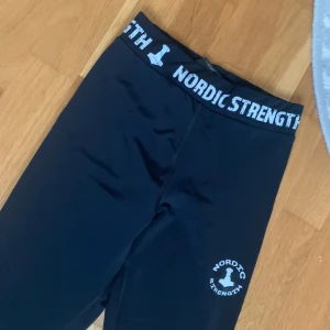Svarta leggings från Nordic Strength - Snygga svarta leggings från Nordic Strength med logga på höften och bred resår i midjan med vit text. Använda endast en gång.