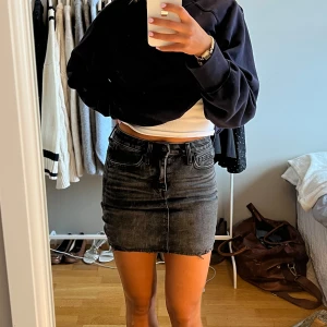 Svart jeanskjol med rå kant - Säljer en svart, tight jeanskjol i kort modell med rå, fransig kant nertill. 