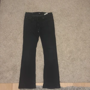Svarta bootcut jeans från LTB - Säljer ett par svarta bootcut jeans från LTB i storlek W26. De är i mycket bra skick och har en klassisk femficksdesign med dragkedja och knapp. Perfekta för både vardag och fest! Passar perfekt på mig som är 1,60