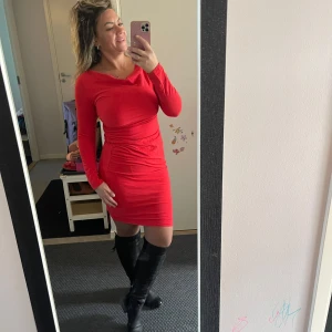 Röd långärmad kortklänning - Säljer en snygg röd klänning med lång ärm och v-ringad hals. Klänningen är figurnära med rynkade detaljer vid midjan och har en kort längd som slutar ovanför knäna. Materialet är mjukt och stretchigt, perfekt för dig som gillar att sticka ut.Bomull,använd en gång passar från S till L