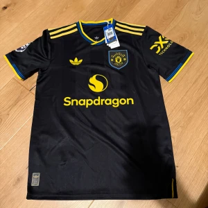 Manchester United svart matchtröja Mbueumo - Svart Manchester United fotbollströja från Adidas. Köpt på unisportstore kvitto finns. Köpte en storlek för liten.