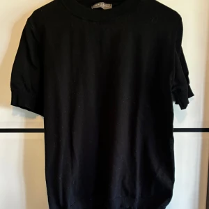 Svart stickad kortärmad tröja - En svart stickad tröja med rund hals och korta ärmar.  Ny pris 1000kr typ! Knappt använd!