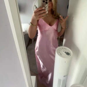 Ljusrosa balklänning - Säljer en superfin ljusrosa långklänning i glansigt satinmaterial. Klänningen har smala axelband, v-ringning och en figurnära passform som ger en elegant look. Perfekt för bal! 💖Från märket By Stina, använd en gång originalpris 1495kr