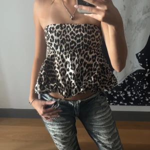 Leopardmönstrad bandeau tubtopp - Säljer en superfin bandeau tubtopp med leopardmönster och volangig peplum-nederdel. Toppen är axelbandslös och har en snygg, luftig passform som ger en cool och trendig vibe. Perfekt för dig som vill sticka ut med ett djurmönster!