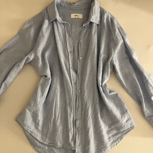 Ljusblå linneskjorta från Gina Tricot - Snygg ljusblå skjorta från Gina Tricot i linnemix. Skjortan har klassisk krage, långa ärmar och knäppning framtill. Perfekt oversized fit för en chill och trendig look. Luftigt material som passar grymt till varmare dagar.