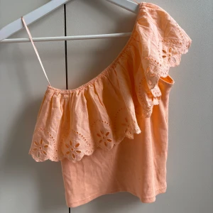 Volang topp - En så fin orange/korall färgad volang topp med one shoulder, perfekt till sommaren och så fin när man är brun! 