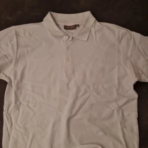 Vit piké och beige skjorta - Säljer en klassisk vit pikétröja från Mac One med krage och tre knappar framtill, samt en beige skjorta i bomull med knappar hela vägen och bröstficka. Perfekt för en clean och avslappnad stil.