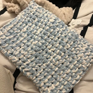 Stickad ljusblå och vit datorväska - Säljer en handgjord stickad datorväska i ljusblått och vitt. Väskan kan köpas som denna eller i annan färg kombination mixad eller ensam färg (vit, brun, grå, blå, svart) 