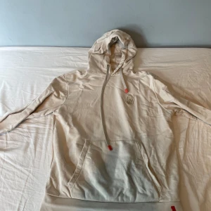 Sail Racing hoodie - Snygg beige Sail Racing hoodie med huva och långa ärmar. Tröjan har en stor magficka och coola röda detaljer på snörena. Liten broderad logga på bröstet. Perfekt för chill dagar eller när du vill ha en enkel och stilren look. Använd ett fåtal gånger. Pris kan diskuteras