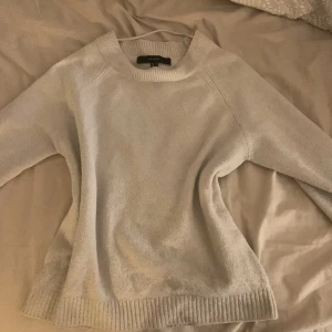 Ljusgrå stickad tröja från Vero Moda - Mysig ljusgrå stickad tröja från Vero Moda i storlek S. Tröjan har rund halsringning, ribbade muddar och är långärmad. Perfekt för lager-på-lager och chill dagar. Enkel och stilren design som funkar till det mesta.