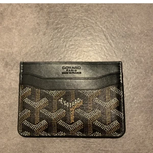 Svart korthållare - Snygg plånbok i svart skinn med det klassiska mönstret i beige och brunt. Plånboken har flera fack för kort och är perfekt för dig som gillar stilrena accessoarer med lyxig känsla. Diskret logga framtill och unik design. Bara att höra av sig vid funderingar, pris kan diskuteras👍😀