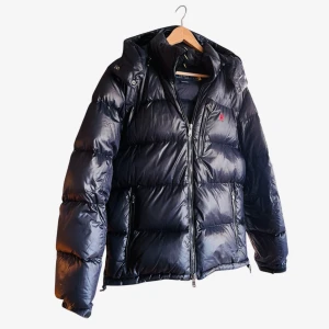 Marinblå Dunjacka från Ralph Lauren - Marinblå Dunjacka från Ralph Lauren i väldigt bra skick! Den är använd i en vinter och säljs på grund av att jag vill testa något nytt! Inga synliga brister eller defekter. Jackan är varm och tjock och perfekt nu för vintern. Nypriset är 6095 och är sällsynt, nästan slutsåld i alla butiker! Smart att köpa nu under off-season för ett billigare pris. Passformen ser ni på bild 4. Tveka inte att fråga om fler bilder/frågor! 