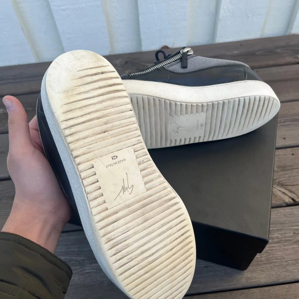 Snygga sneakers från Giuseppe Zanotti i grått och svart med coola dragkedjor på sidorna. Skorna har en rund tå och snörning, vilket ger en modern look. Nypris på dessa ligger på ca 3800kr. Medföljer OG box. Skorna är i bra skick.. Kengät.