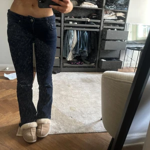 Mörkblå jeans med bootcut - Snygga mörkblå jeans med bootcut och slitningar på knäna. De har en klassisk femficksdesign och stängs med dragkedja och knapp. Perfekta för en avslappnad stil.