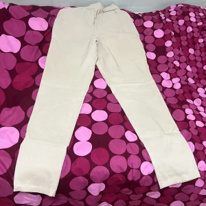 Beige kostymbyxor - Snygga beige kostymbyxor med hög midja och en elegant, smal passform. Perfekta för en stilren look. De är tillverkade i ett mjukt material som ger en bekväm känsla hela dagen.