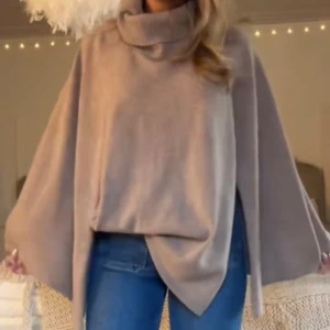 Poncho  - Säljer en supermysig beige oversized polotröja med breda ärmar. Perfekt för kyliga dagar när du vill ha något bekvämt och stilrent. Tröjan har en hög polokrage som ger extra värme och stil. Passar perfekt till jeans eller leggings.