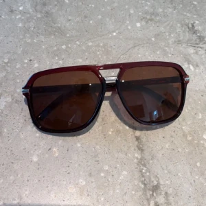 Solglasögon rayban boyfriend  - Snygga solglasögon med en djup röd båge och bruna linser. De har en klassisk design med en metallbro över näsan och breda skalmar. Perfekta för att ge en cool touch till din stil. MÖTS UPP I HELSINGBORG ELLER KÖPS VIA MITT VINTED KONTO, SKRIV PRIVAT