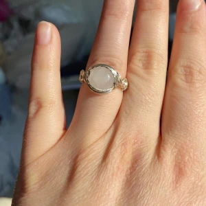 Silverring med rosenkvart  - Elegant silverring med detaljerade silvertrådar som omsluter stenen och ger ett unikt utseende. Perfekt för att ge en stilren touch till din outfit.