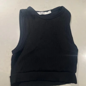 Svart ribbad linnetopp från NA-KD - Säljer en stilren svart ribbad linnetopp från NA-KD. Cropped. 