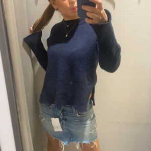 Svart stickad tröja från GANT - Säljer en stilren mörkblåa stickad tröja från GANT. Tröjan har en klassisk design med ribbstickad krage och långa ärmar. Perfekt för kyliga dagar. Passar bra till både jeans och kjol.