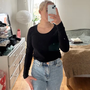 Svart långärmad topp - Säljer en stilren svart långärmad topp med rund hals. Perfekt för lager-på-lager eller att bära som den är. Passar till både jeans och kjol.