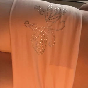Rosa y2k 2000s yoga pants - Snygga rosa byxor med en glittrig fjärilsdetalj på höften. Byxorna har en tight passform upptill och vida ben. Perfekta för en trendig look!