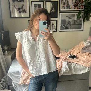 Vit blus med volangdetaljer - Säljer en söt vit blus med volangdetaljer vid ärmarna och en v-ringad hals❣️