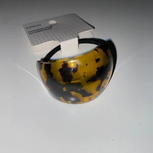 Håraccessoar från Miniso - Snygg håraccessoar från Miniso med ett leopardmönstrat plastspänne i bruna och gula toner. Perfekt för att ge en trendig touch till din frisyr.