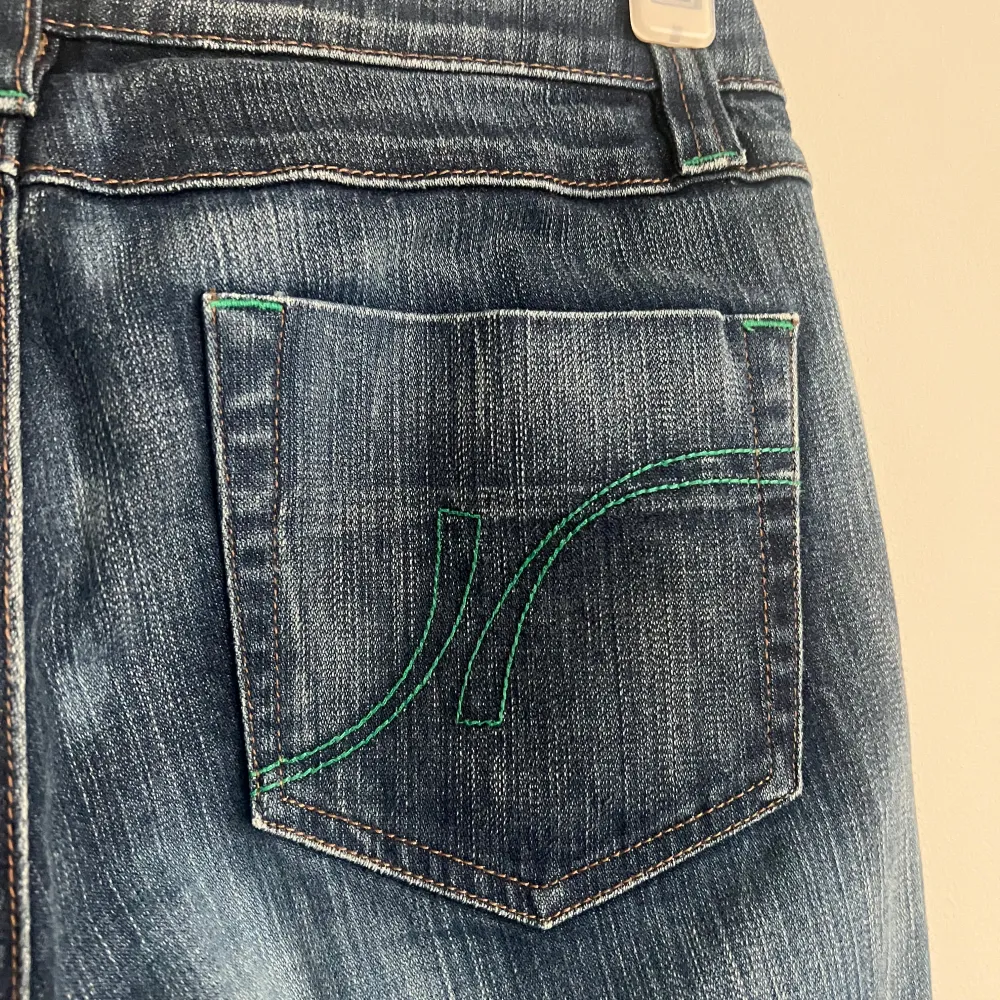 Snygga blå jeans från VM med gröna sömmar på bakfickan. Klassisk femficksdesign och knappgylf. Perfekta för en avslappnad stil.. Farkut & Housut.
