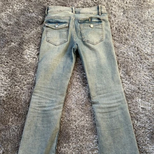 Blåa lågmidjade bootcut jeans - Snygga blå jeansbyxor med bootcut och dubbla knappar i midjan. Klassisk design med fem fickor och dragkedja. Tryck på KÖP NU så postar jag så snabbt jag kan!! 💗