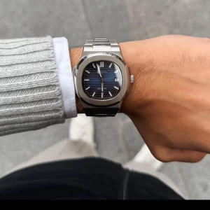 Elegant silverfärgad klocka med blå urtavla - Snygg och stilren klocka med silverfärgat armband och en djupblå urtavla. Perfekt för den som vill ha en tidlös accessoar med en modern touch. Klockan har en robust design och passar till många olika stilar.