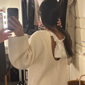 Vit stickad tröja med öppen rygg och rosett -  mysig stickad vit tröja från gina tricot med öppen rygg i strl S, aldrig använd.