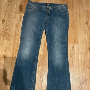 Blå jeans från Lee - Snygga blå jeans från Lee med klassisk femficksdesign och dragkedja. De har en bekväm passform och är perfekta för en avslappnad stil. Märkeslogga på baksidan ger en extra touch.
