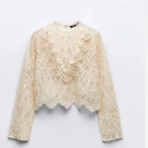 Beige spetsblus - Elegant beige spetsblus med långa ärmar och vackra detaljer. Perfekt för en stilfull look med sitt intrikata mönster och romantiska känsla.