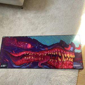 Stor musmatta med monsterdesign från X-Gamer - Säljer en stor musmatta från X-Gamer med en häftig monsterdesign i rött, blått och gult. Perfekt för gaming och ger en cool look till skrivbordet. Designen är detaljerad med ett monsteransikte som har skarpa tänder och intensiva ögon.