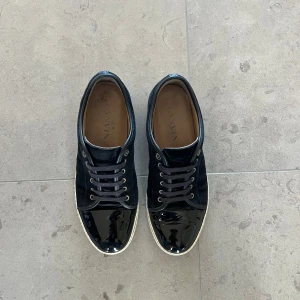 Marinblå sneakers från Lanvin - Snygga navy blå sneakers från Lanvin. De är i storlek Uk9/43 men sitter lite större, passar 44. Små deffekter på cap toesen men inget som syns från längre avstånd. Endast skorna tillkommer. Hör av dig vid frågor eller köp.