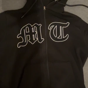 Svart zip hoodie från Tuttolente Medium - Säljer en svart hoodie från tuttolente med dragkedja och stort tryck fram. Baksidan har ett diskret mönster av en örn. Den är i bra skick, storlek M men passar S. Kostar ca 1100 ny