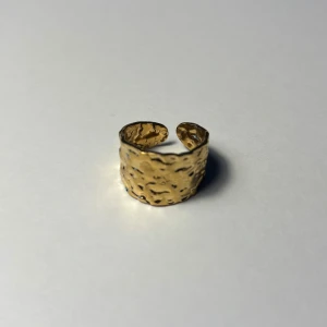 Guldfärgad justerbar ring - Elegant guldfärgad ring med en hamrad yta som jag hitta på Humana. Ringen är justerbar och passar de flesta storlekar. Perfekt för att ge en stilfull touch till din outfit.