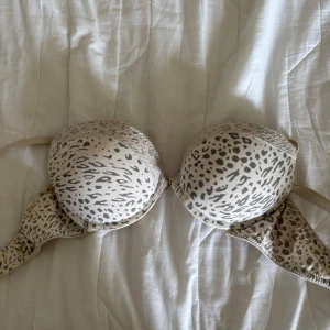 Leopardmönstrad Pusch up bh från H&M - Säljer en snygg leopardmönstrad Pusch up bh från H&M i beige och grå toner. Bh:n har vadderade kupor och justerbara axelband för bästa passform. Perfekt för dig som vill ha något både bekvämt och stilrent. Ena bygeln har kommit lite ur form men inget som syns om man har den på se sista bild 