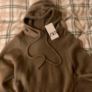Beige croppad hoodie från Zara - Säljer en snygg beige croppad hoodie från Zara. Den är super mysig men ändå inte stickig. Perfekt för en avslappnad stil. Passar jätte fint till ett par lågmidjade jeans. Aldrig använt, nypris:550kr