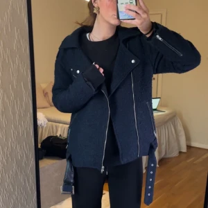 Mörkblå jacka med dragkedja - Snygg mörkblå jacka med dragkedja och bälte. Jackan har en texturerad yta och långa ärmar. Perfekt för våren eller kallare kvällar dagar. Samma stil som en skinnjacka fast i mjukt material. Från Bikbok 