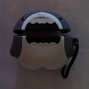 Grå och vit plånbok med karbinhake - Säljer ett AirPods skal för dom breda AirPodsen. I form av en blå och vit haj. Kommer med en karbinhake för att kunna sätta fast den i diverse saker.