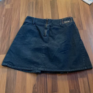 Mörkblå jeanskjol från Street One - Säljer en snygg mörkblå jeanskjol från Street One. Kjolen har en dragkedja bak och en klassisk A-linjeformad design. Perfekt för en avslappnad stil. Säljer för att den är för stor på mig.