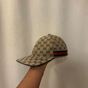 Gucci keps - Beige keps från Gucci! Kepsen köptes i slutet på förra året och är i riktigt bra skick. Har användes få gånger och kommer inte mer till användning och är där med ute på salu.