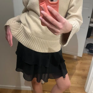 Svart volangkjol  - Säljer en svart kortkjol med dubbla volanger i ett lätt och fladdrigt material. Kjolen har en enkel, stilren design och är perfekt för dig som gillar en feminin och trendig look.