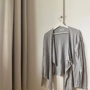 Grå kofta - Lätt och tunn grå kofta. Modellen är öppen framtill utan knappar och har långa ärmar. Perfekt att slänga på sig över en topp för en avslappnad look. Pris diskuteras💘
