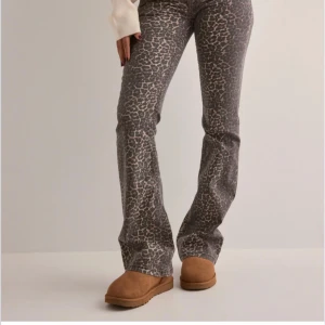 Leopardmönstrade bootcut byxor - Säljer ett par snygga bootcut byxor med leopardmönster. Byxorna har en normal passform och är perfekta för dig som vill sticka ut lite extra. Färgen går i gråbruna toner och materialet känns mjukt och bekvämt.